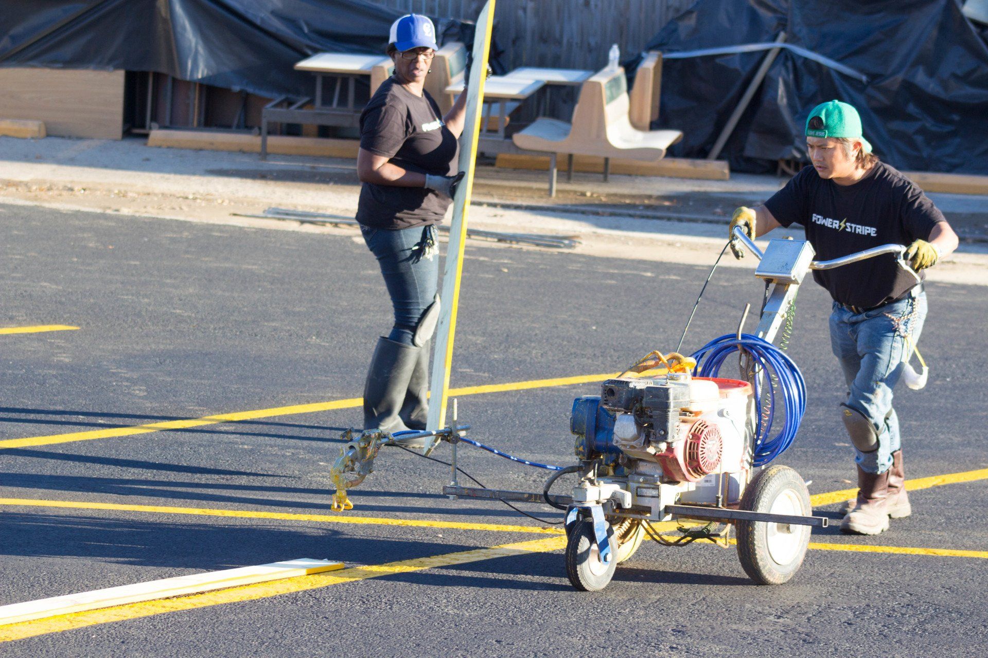 Two men are painting yellow lines on the road
