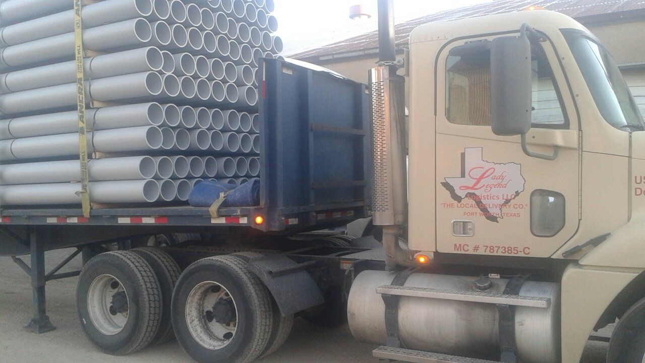 A semi truck is carrying a stack of pipes.