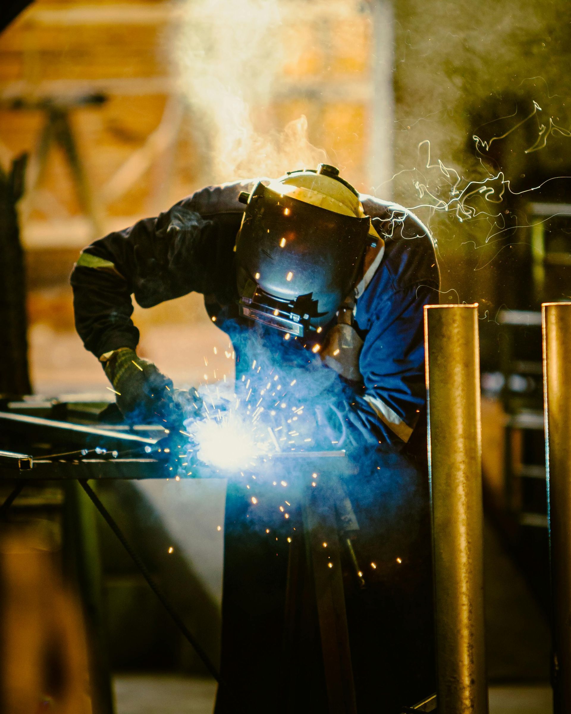 A man wearing a welding mask is welding a piece of metal.