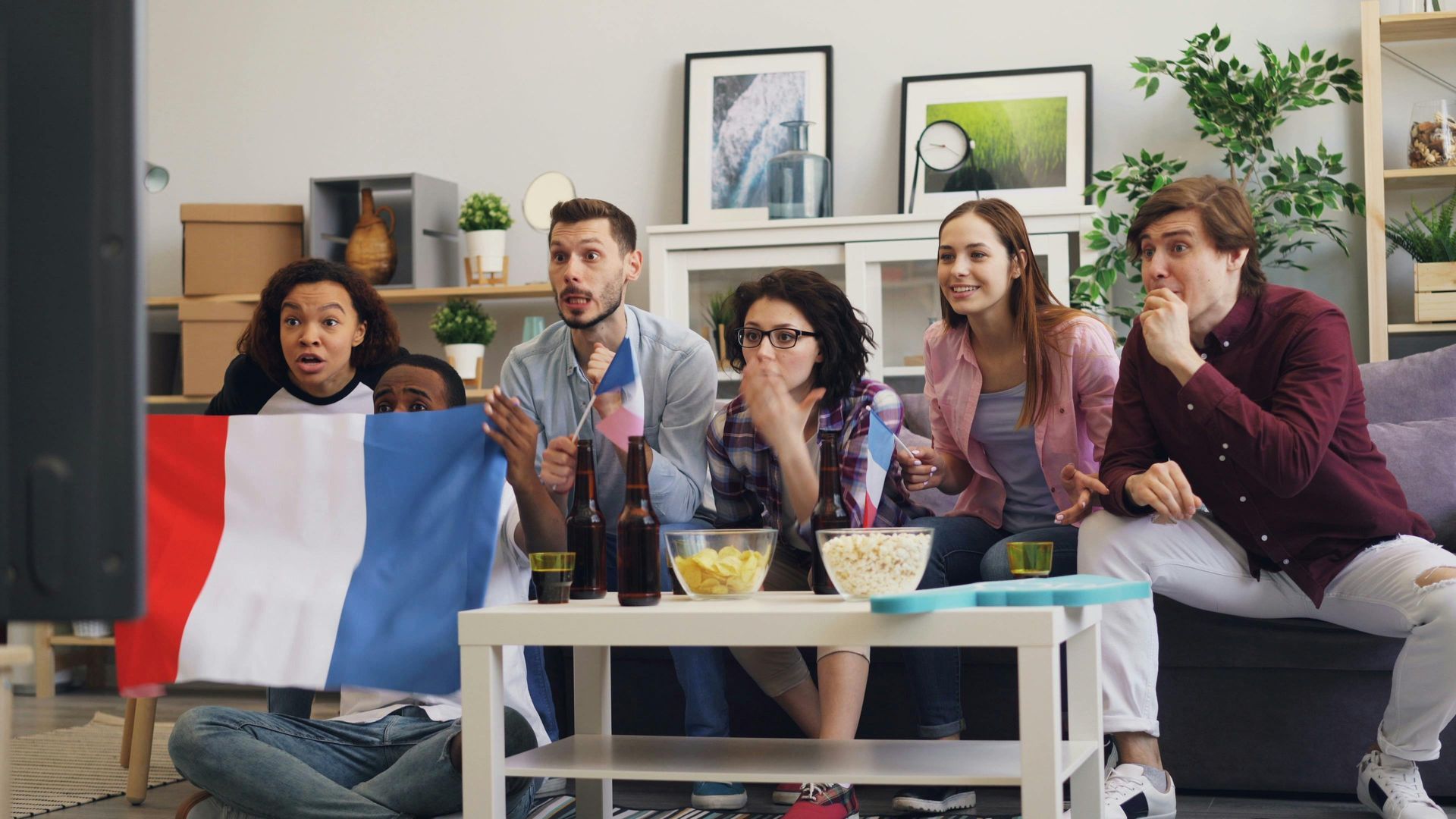 A group of people are sitting in a living room watching a soccer game.