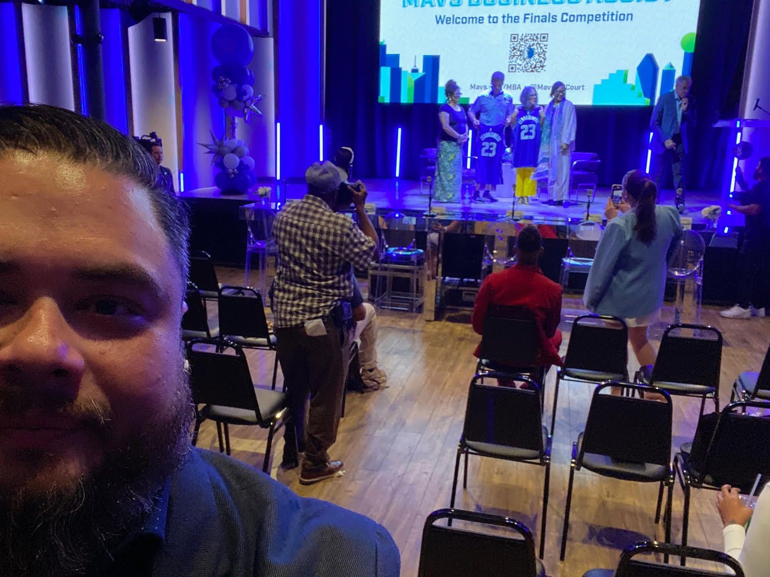 A man is taking a picture of a group of people sitting in chairs in a room.