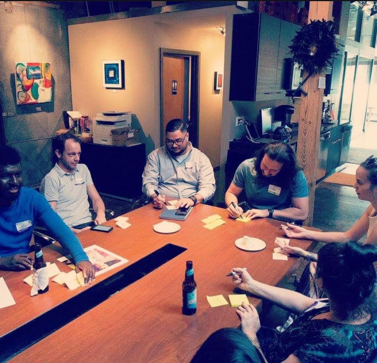 A group of people are sitting at a table with plates of food and drinks.