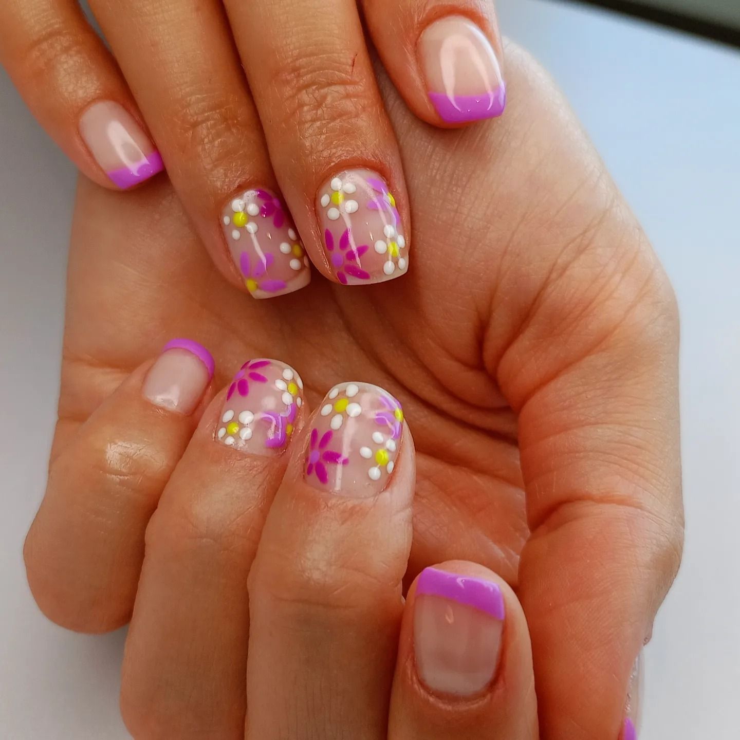 Un primo piano delle unghie di una donna con dei fiori sopra