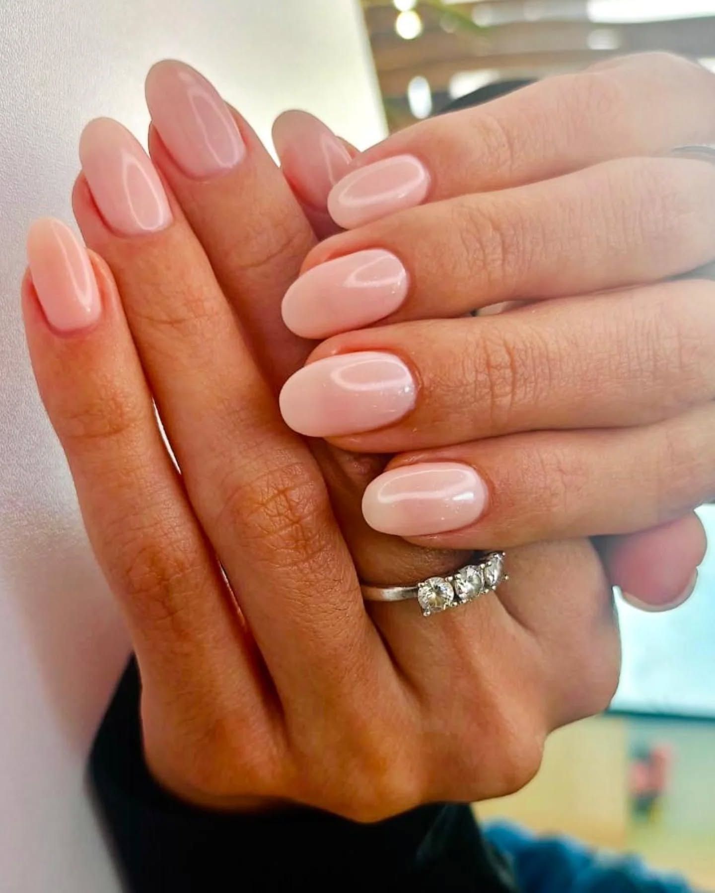 Un primo piano delle mani di una donna con le unghie rosa e un anello al dito.