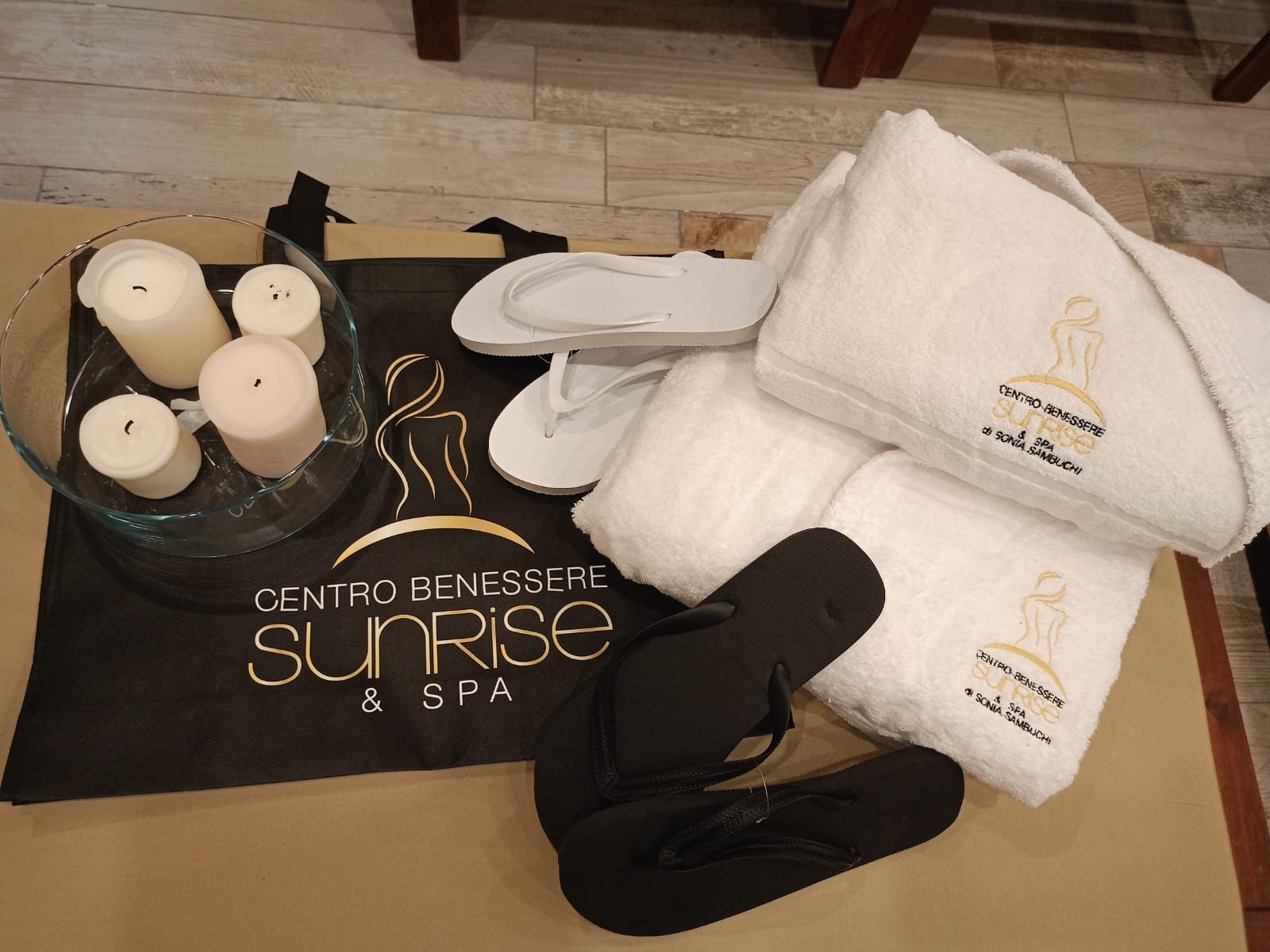 Asciugamani e infradito su un tavolo con scritto centro benessere sunrise spa
