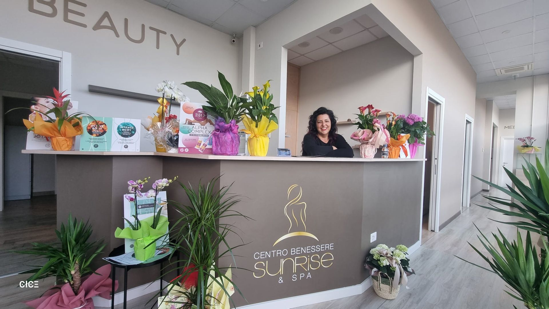 Una donna è seduta al bancone di un salone di bellezza circondata da fiori.