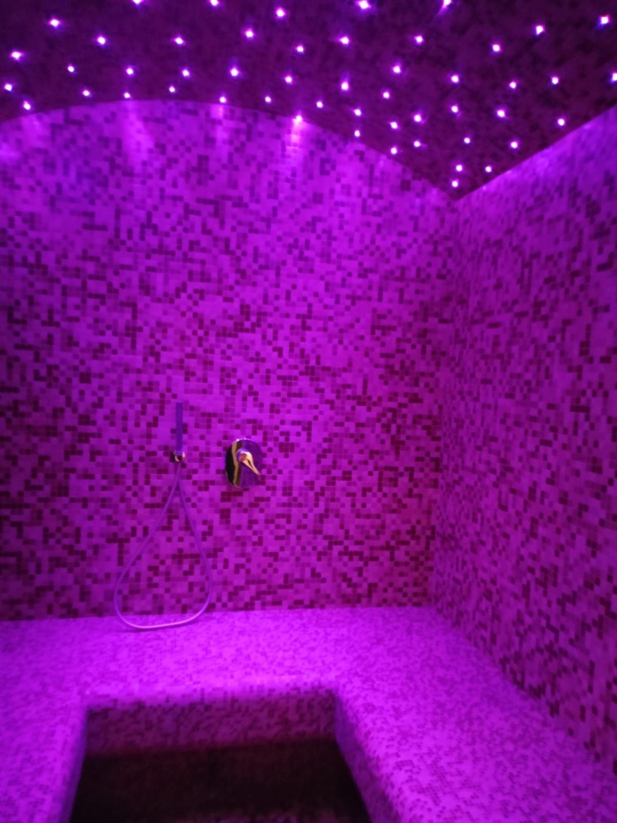 Un bagno viola con luci viola sul soffitto e sulle pareti.