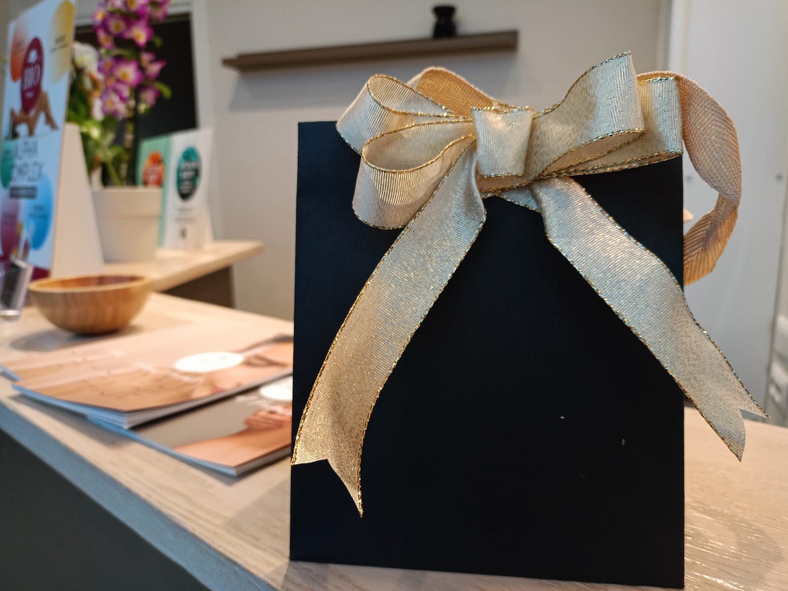 Una borsa regalo nera con un fiocco dorato è appoggiata su un bancone