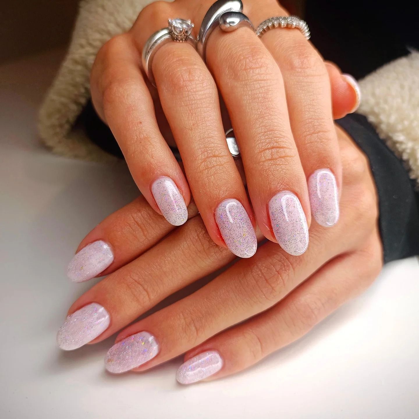 Le mani di una donna con unghie rosa e anelli alle dita