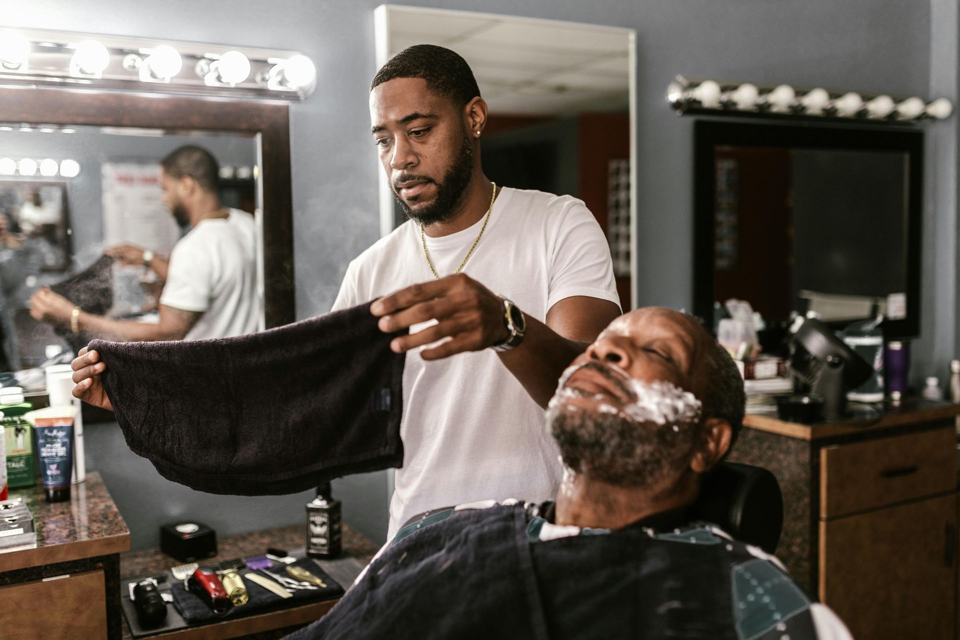Barber holding a towel, preparing to shave a customer's face in a barbershop.