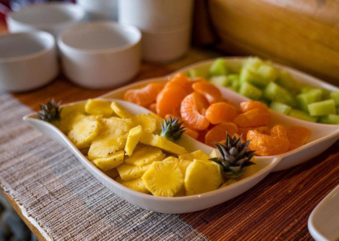 A plate of fruit is sitting on a wooden table.