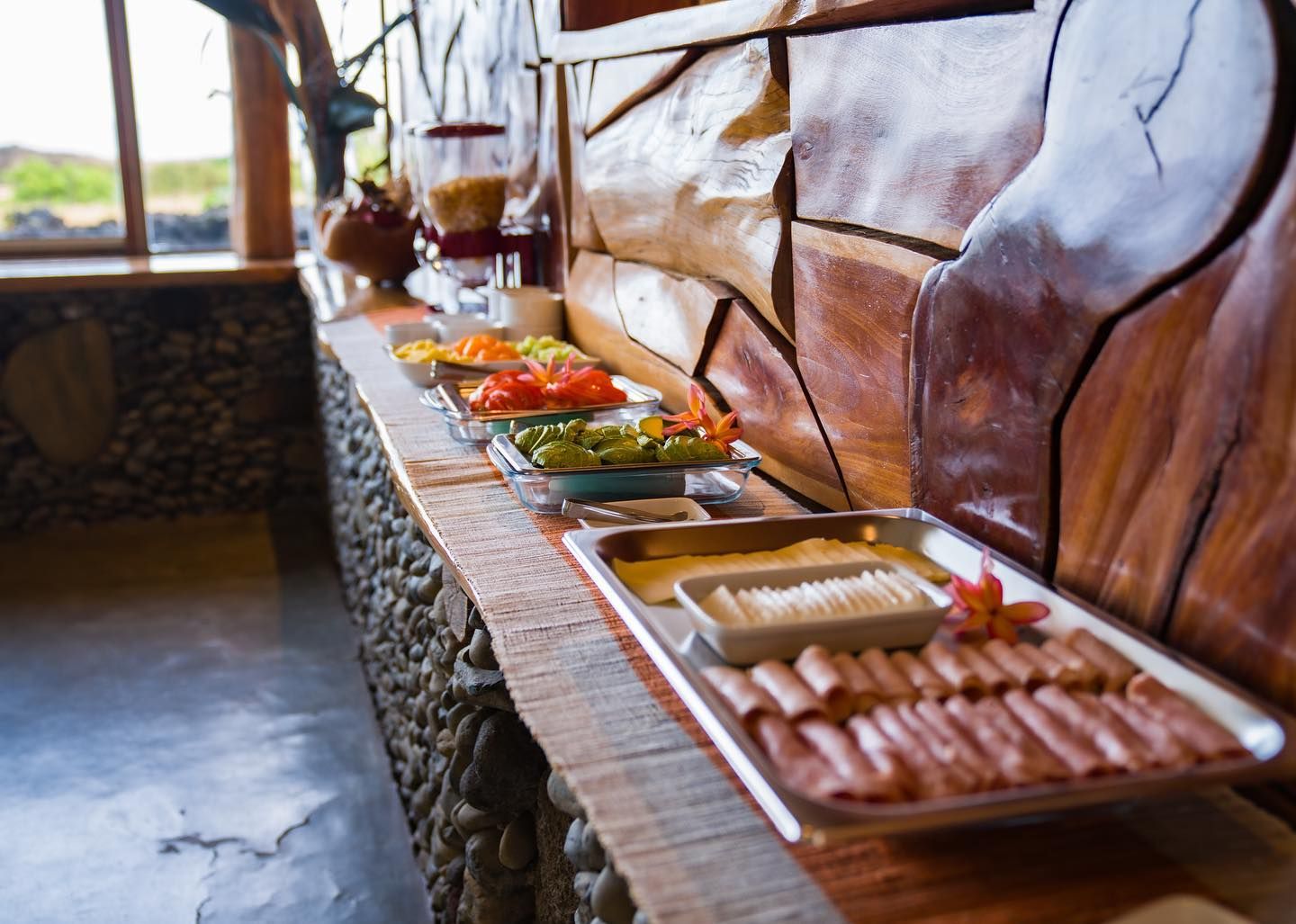 A buffet table with plates of food on it in front of a wooden wall.
