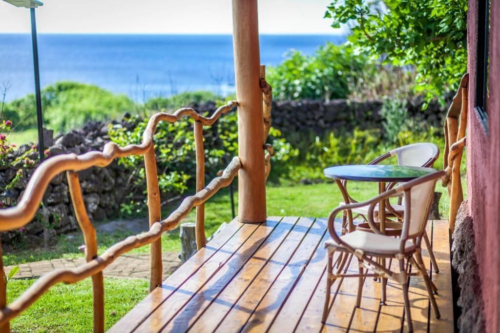 A wooden porch with a table and chairs overlooking the ocean.