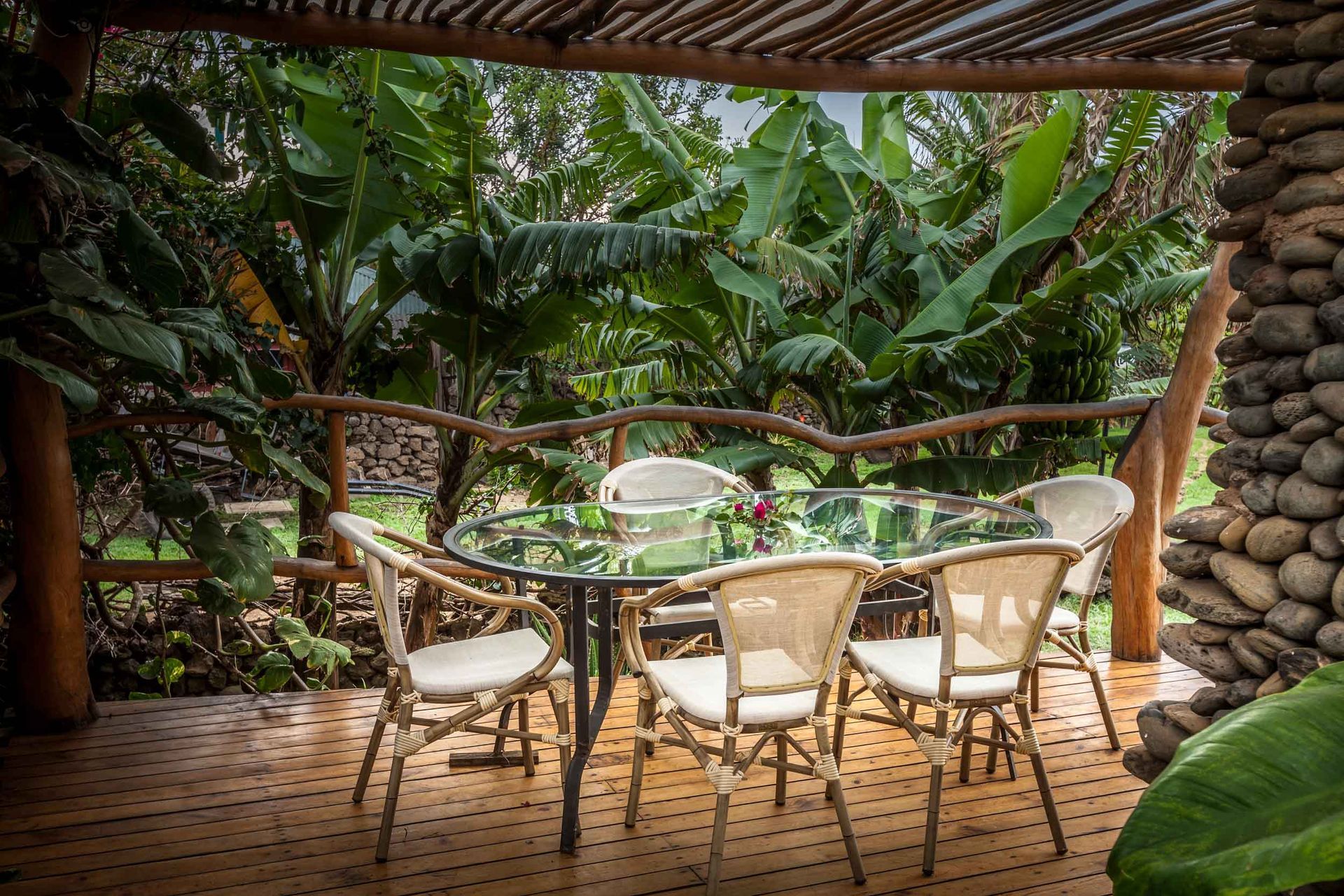 A table and chairs are sitting on a wooden deck under a canopy.