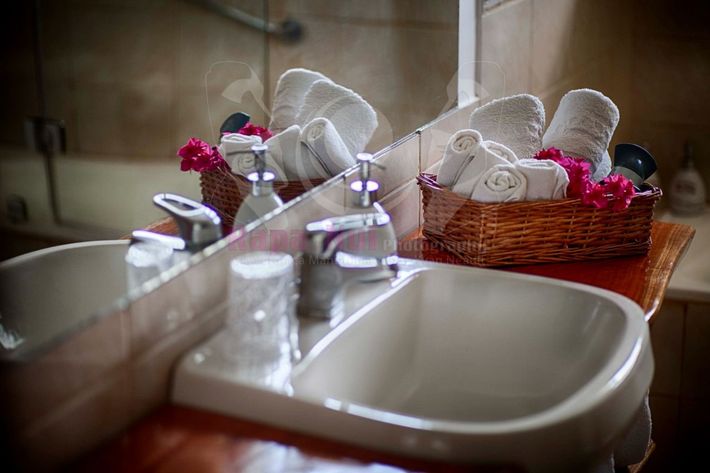 A bathroom sink with a basket of towels on top of it.