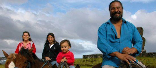 A man and three children are riding horses in a field.