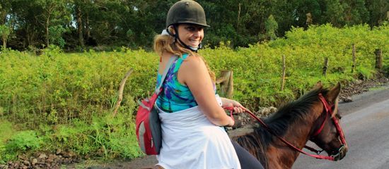 A woman is riding a horse down a dirt road.