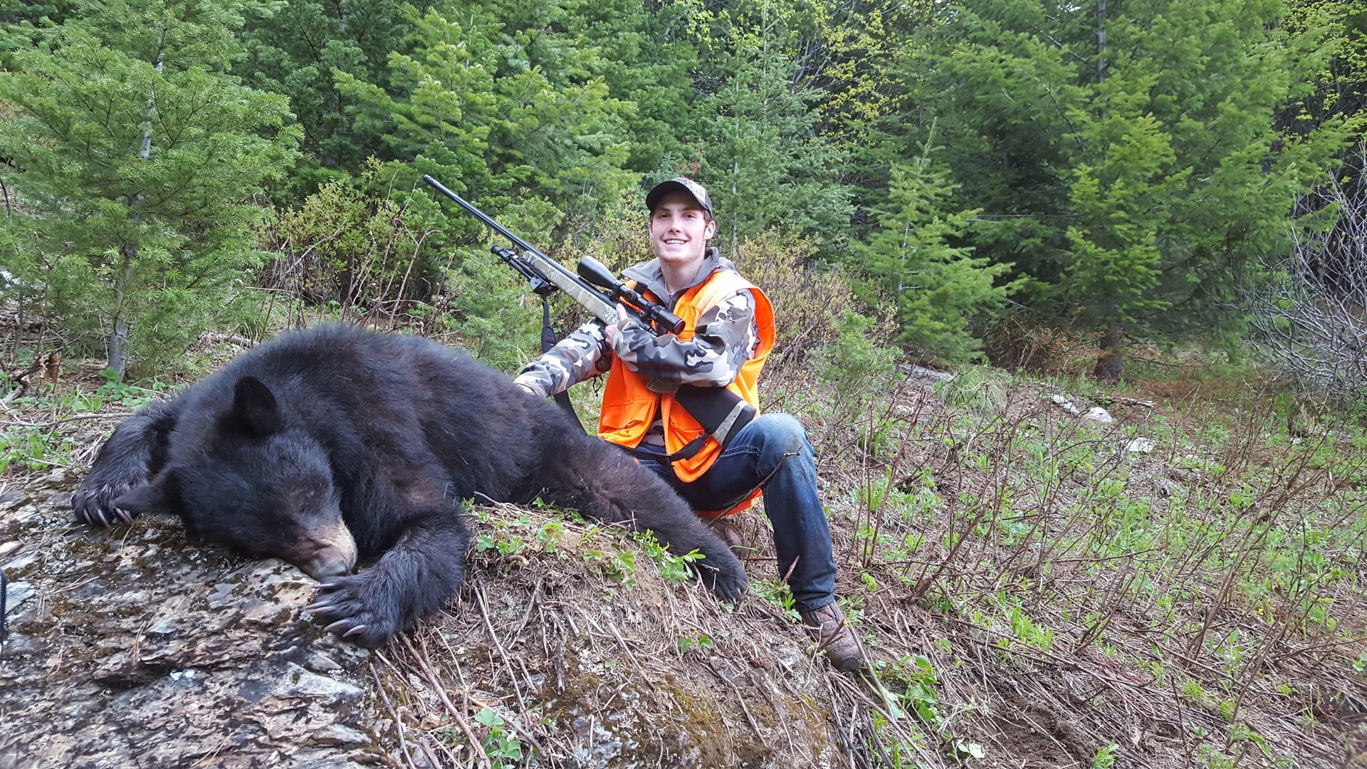 A black bear is laying on its back in the snow.