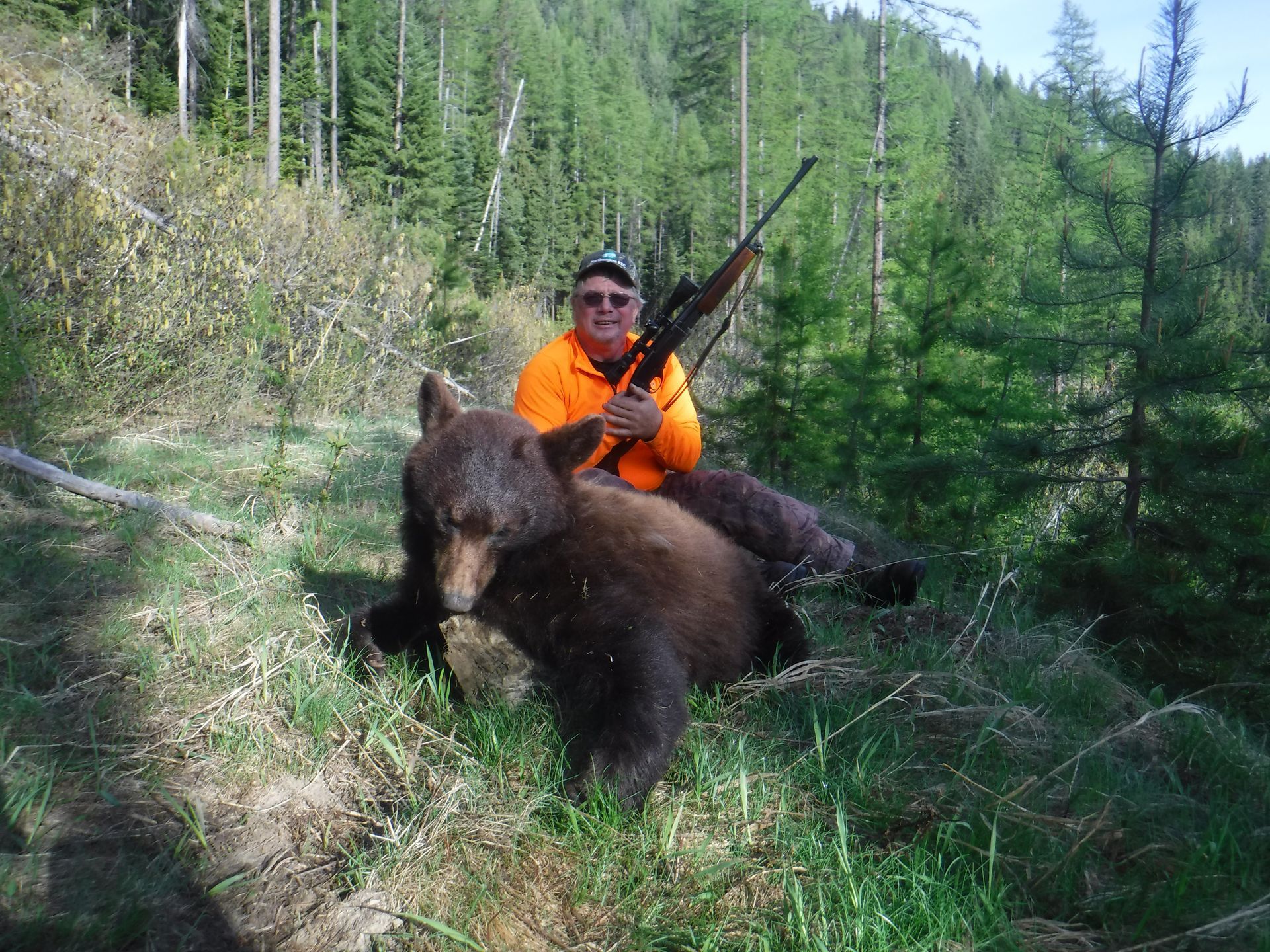 A black bear is laying on its back in the snow.