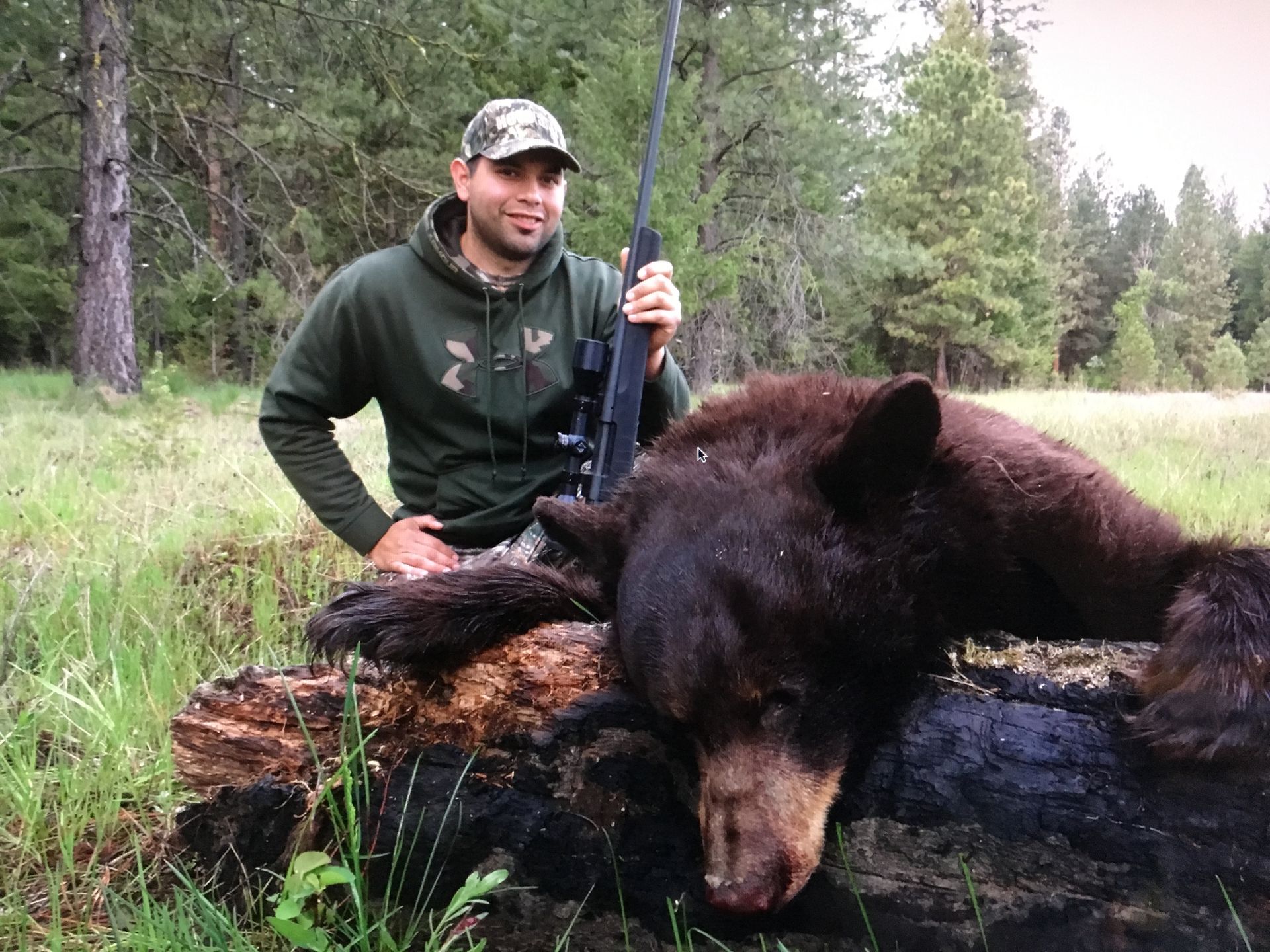 A black bear is laying on its back in the snow.