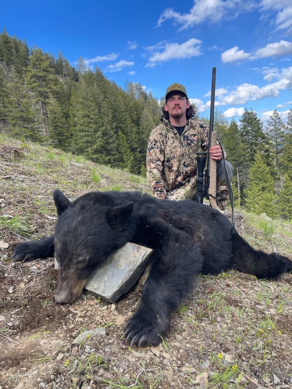 A black bear is laying on its back in the snow.