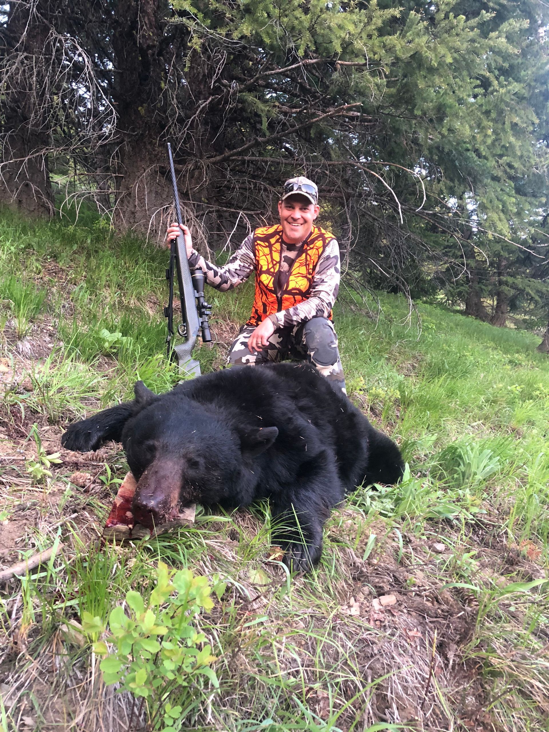 A black bear is laying on its back in the snow.