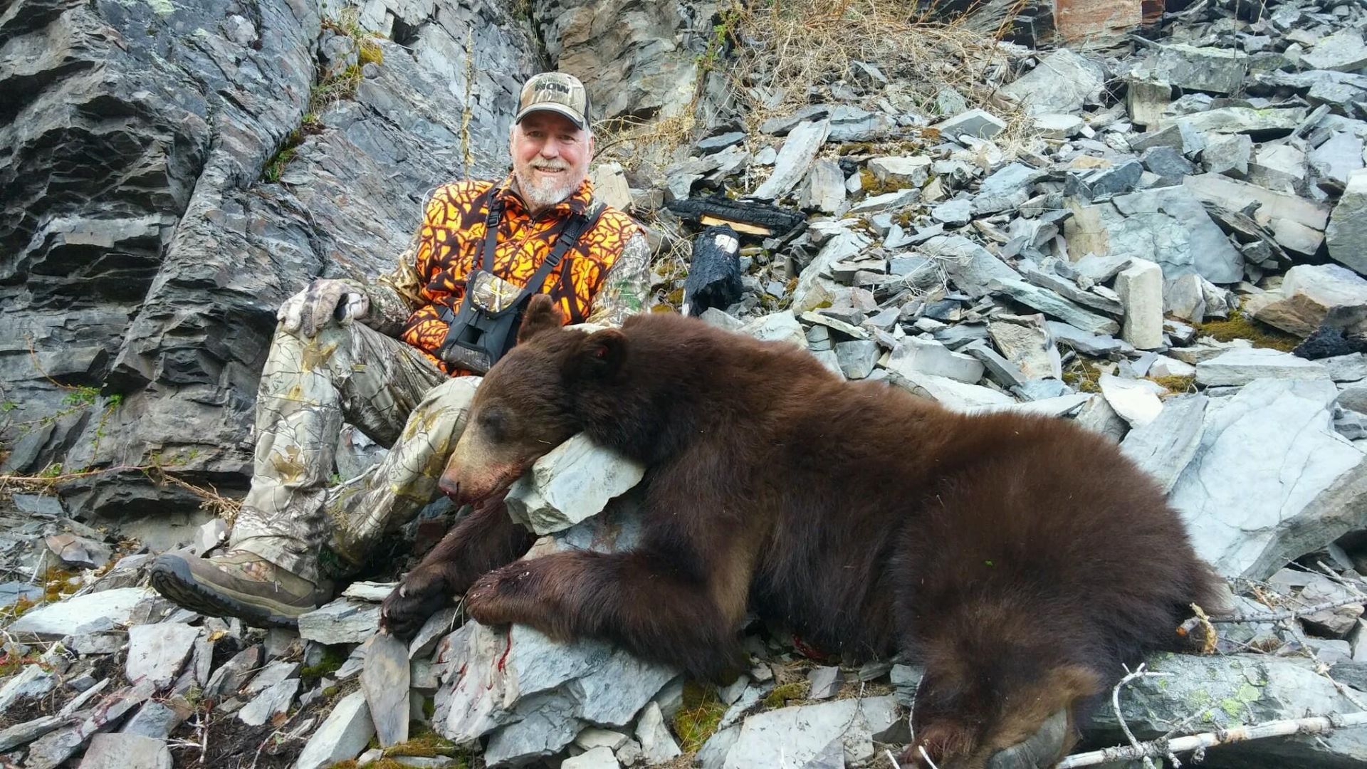 A black bear is laying on its back in the snow.