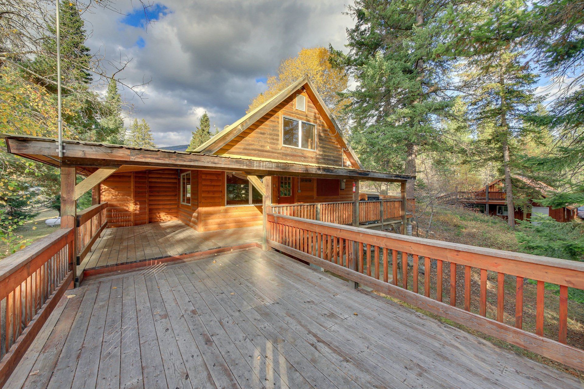 A wooden deck leading to a log cabin in the woods.
