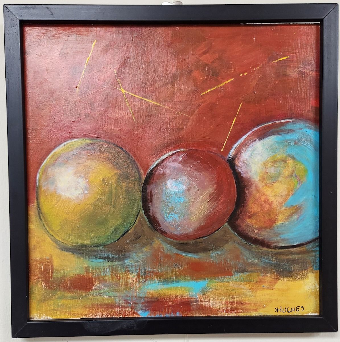 Abstract painting of three spheres: yellow, red, and blue-toned, against a red-orange backdrop with gold lines.