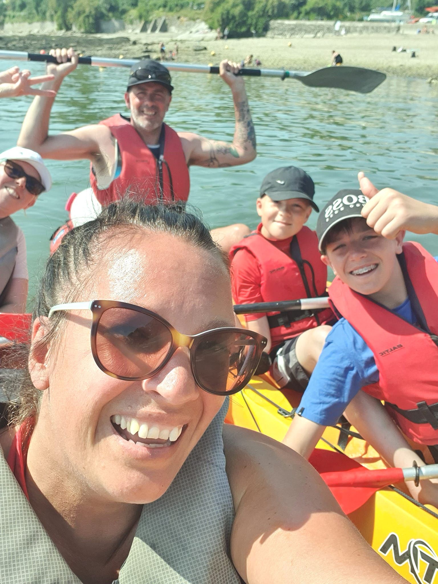 A woman is taking a selfie with her family in a kayak.