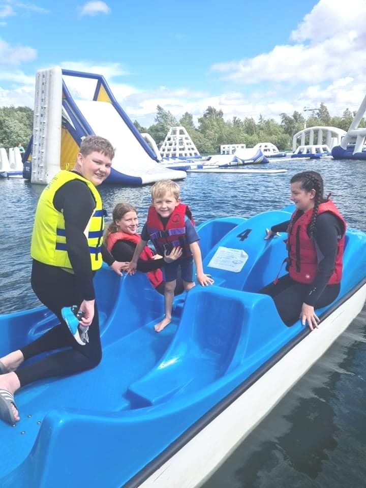 A group of people are riding a blue boat on a lake