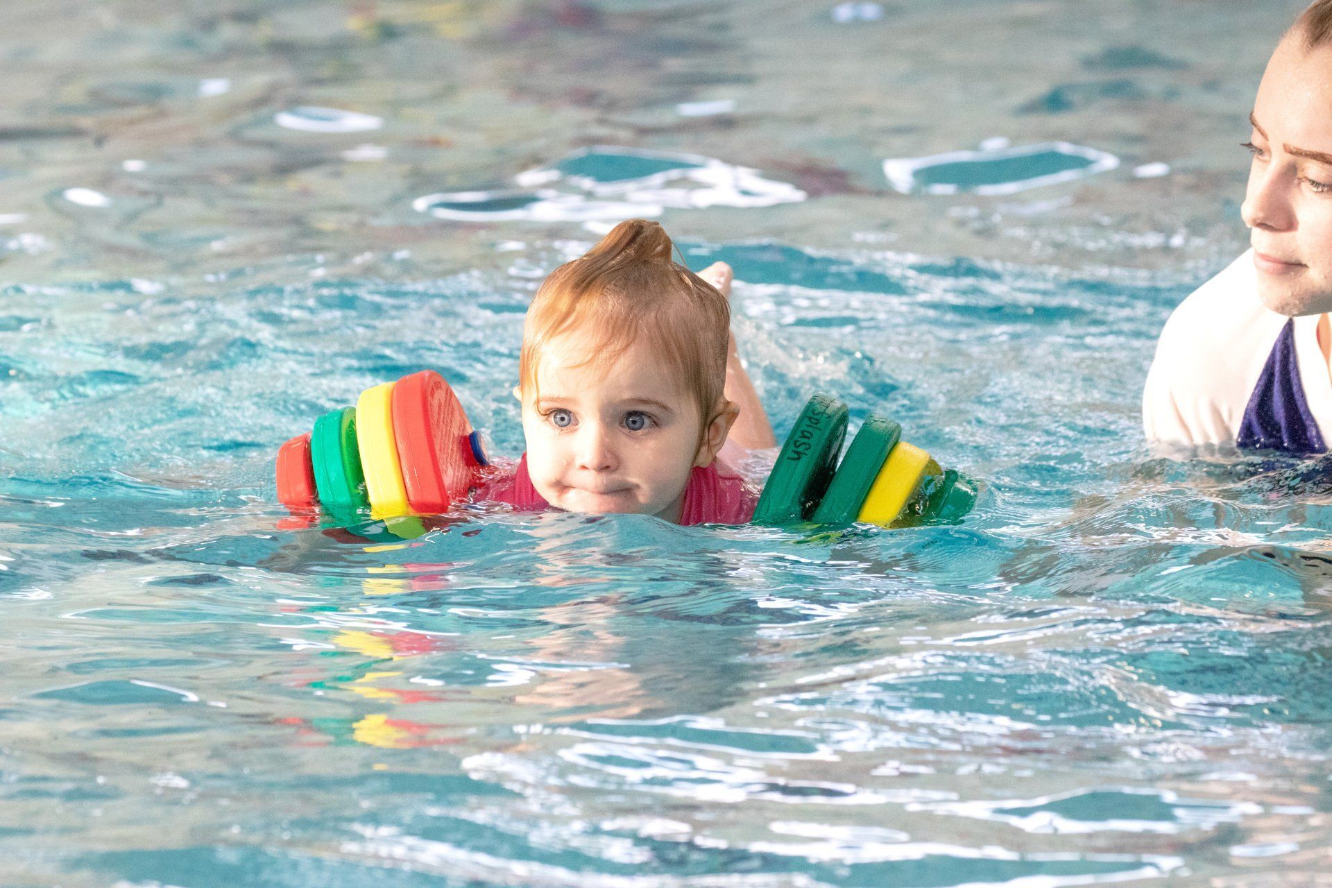 A little girl is swimming in a swimming pool.