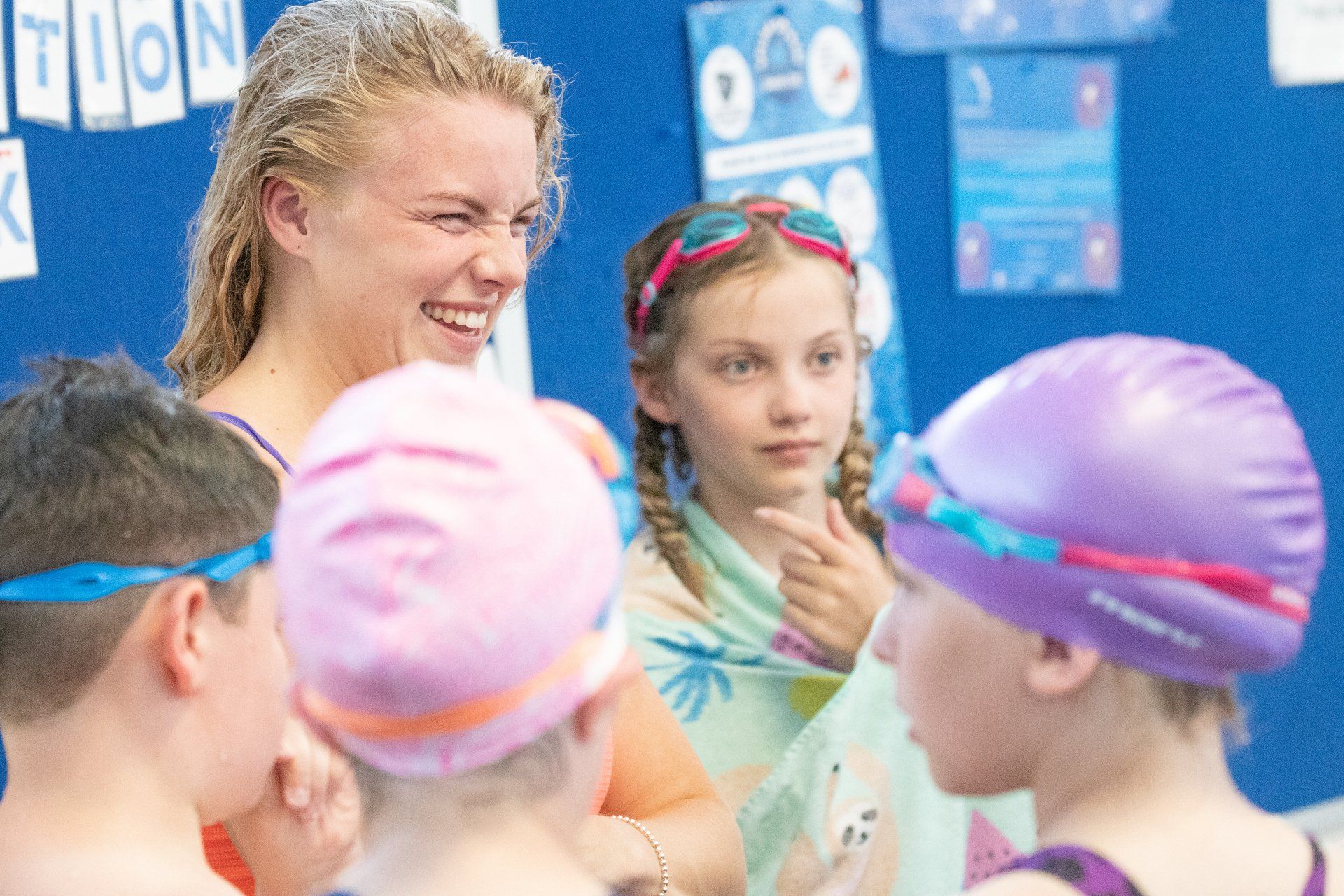 A woman is talking to a group of children in a swimming pool.