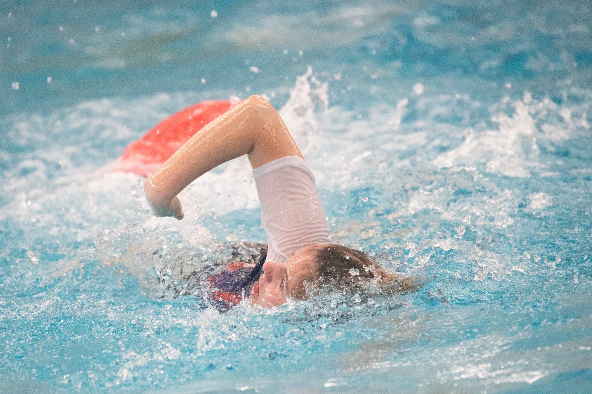 A young girl is swimming in a swimming pool.