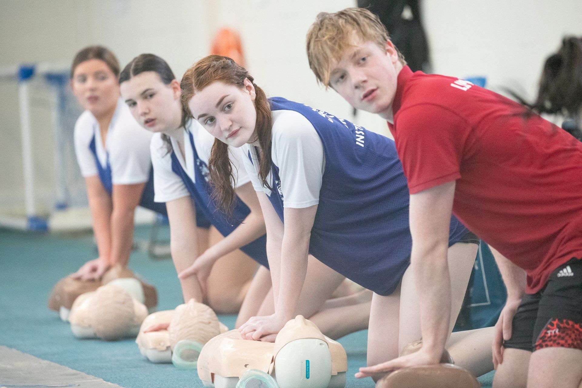 A group of young people are practicing first aid on a mannequin.