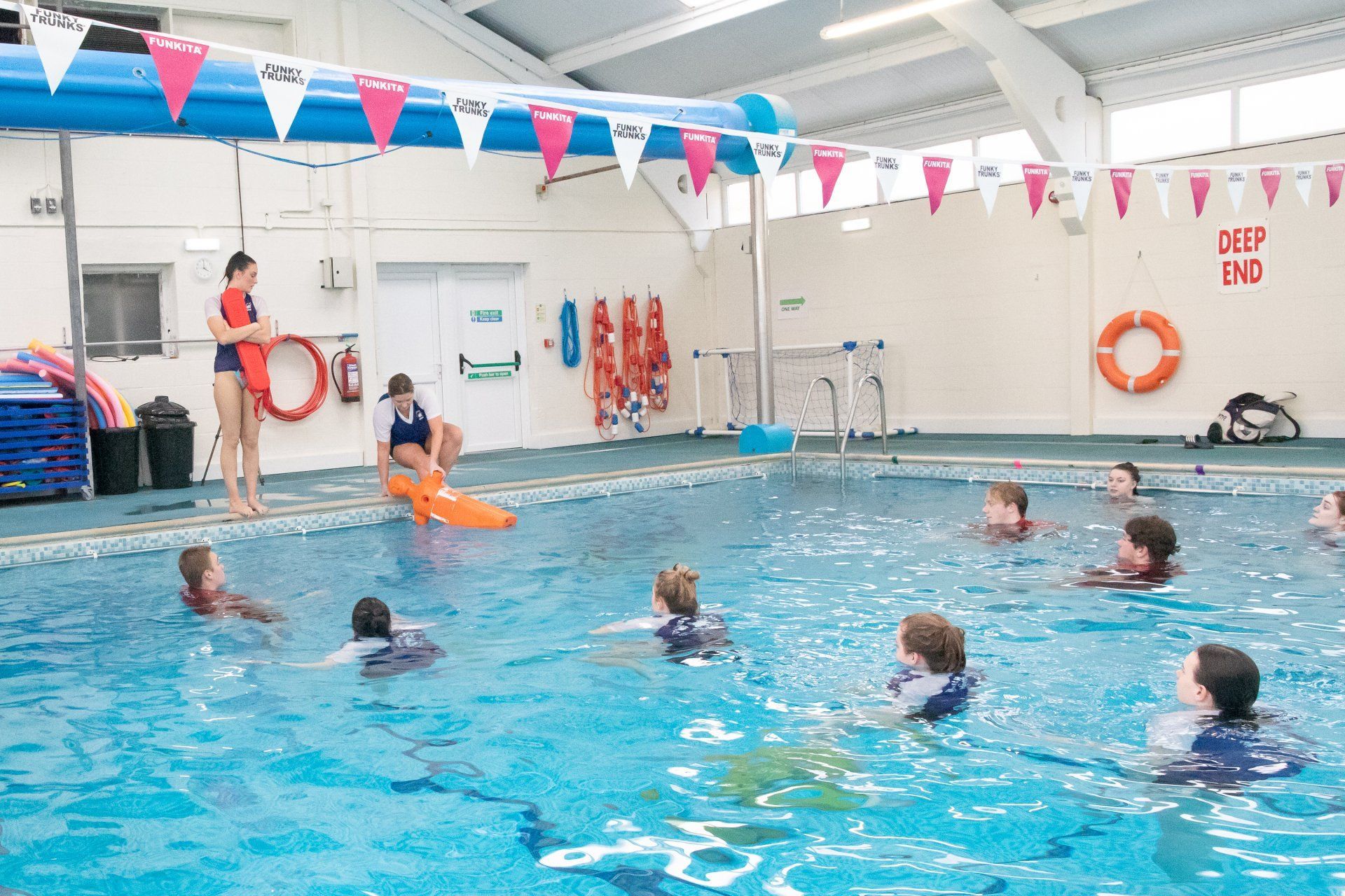 A group of people are swimming in a large indoor swimming pool.