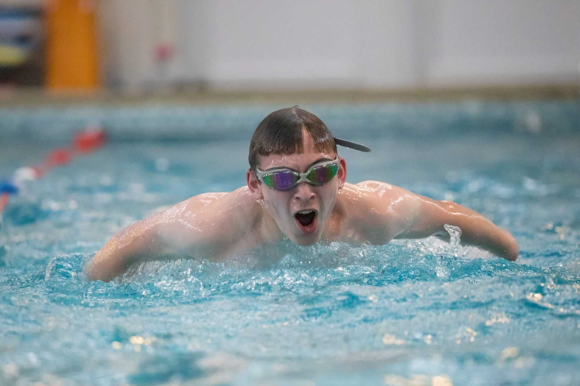 A young boy is swimming in a swimming pool wearing goggles.