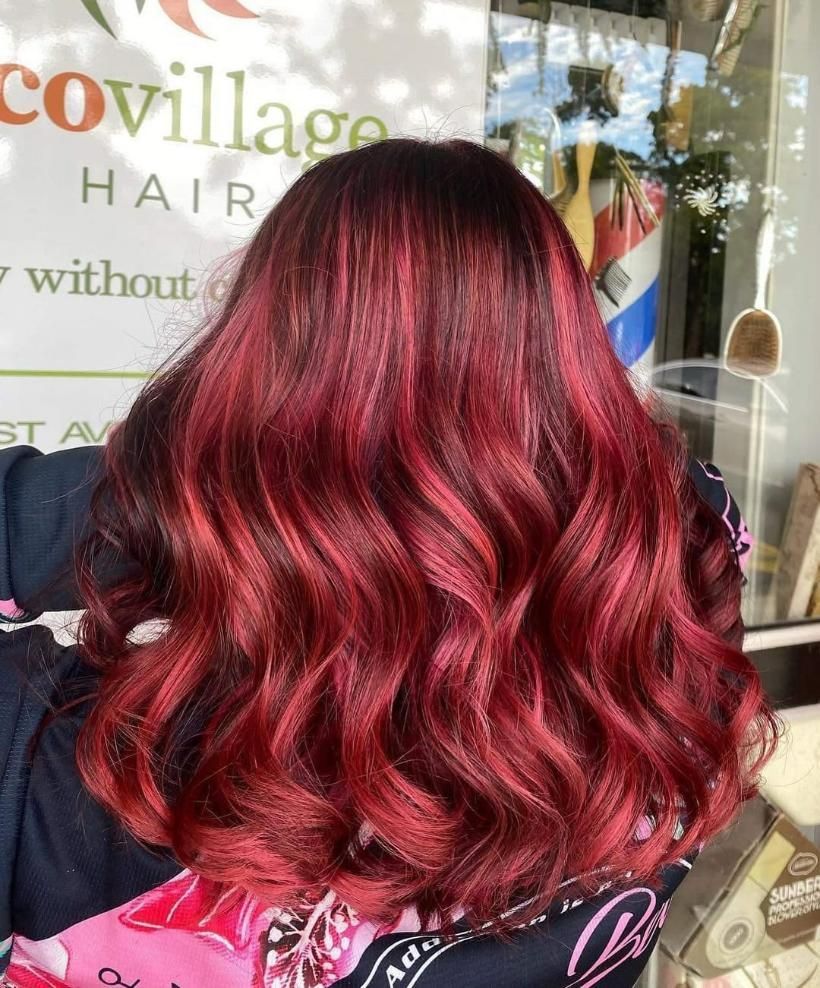 A Woman with Long Red Hair Is Standing in Front of A Window — Eco Village Hair in Bongaree, QLD