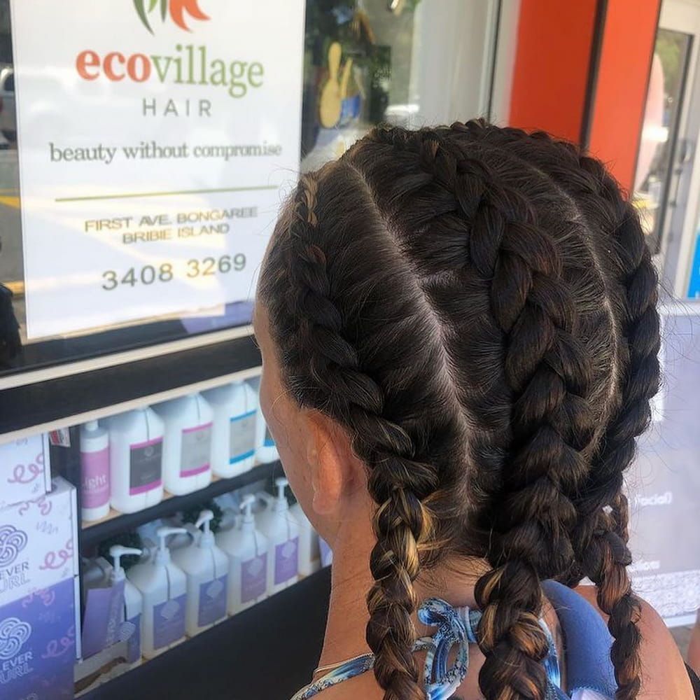 A Woman With Braids in Front of a Sign That Says Ecovillage Hair — Eco Village Hair in Bongaree, QLD