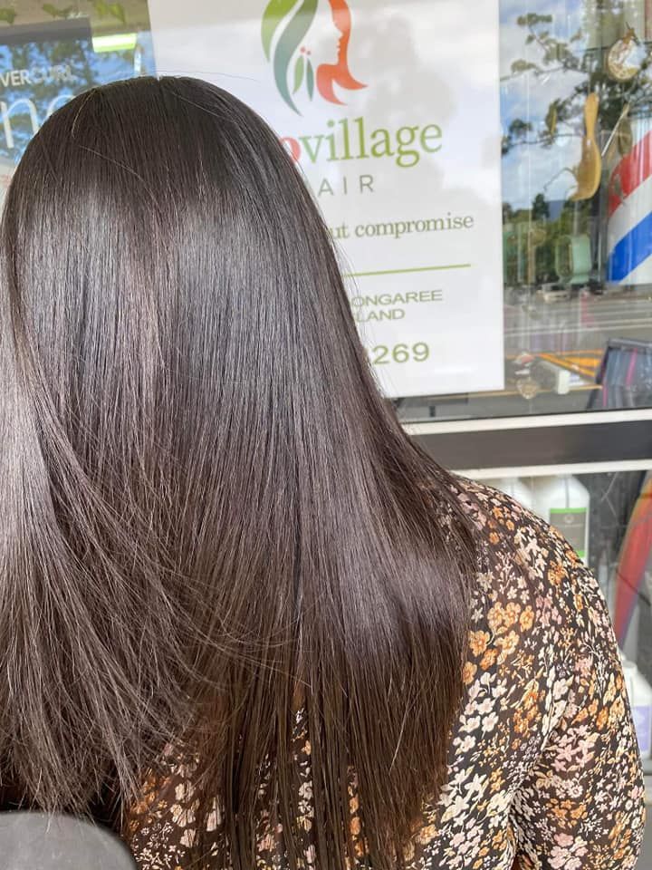 A Woman is Standing in Front of a Sign That Says Village Hair — Eco Village Hair in Bongaree, QLD
