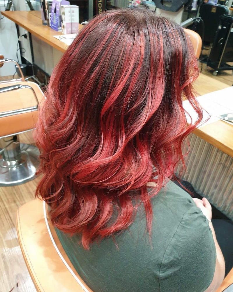 A Woman With Red Hair is Sitting in a Chair in a Salon — Eco Village Hair in Bongaree, QLD