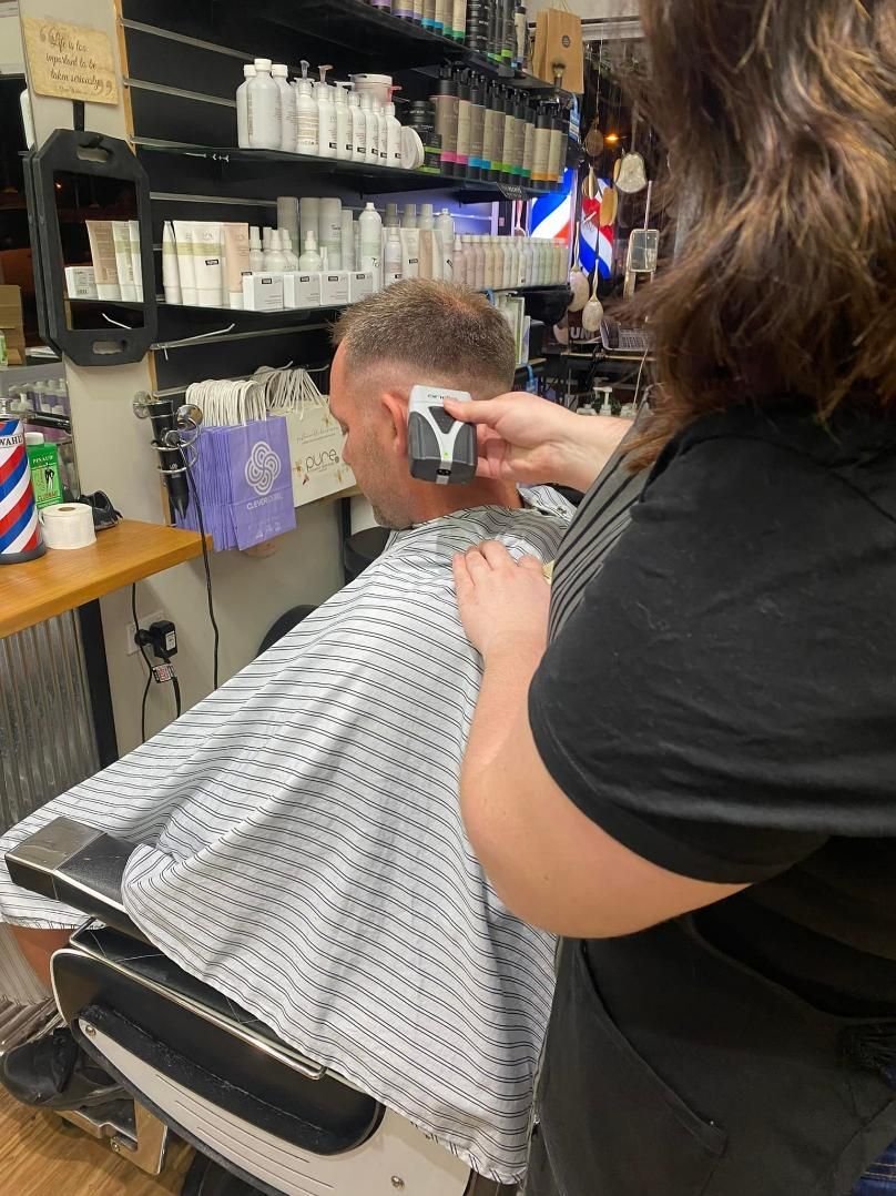 A Woman Is Cutting a Man's Hair in A Barber Shop — Eco Village Hair in Bongaree, QLD