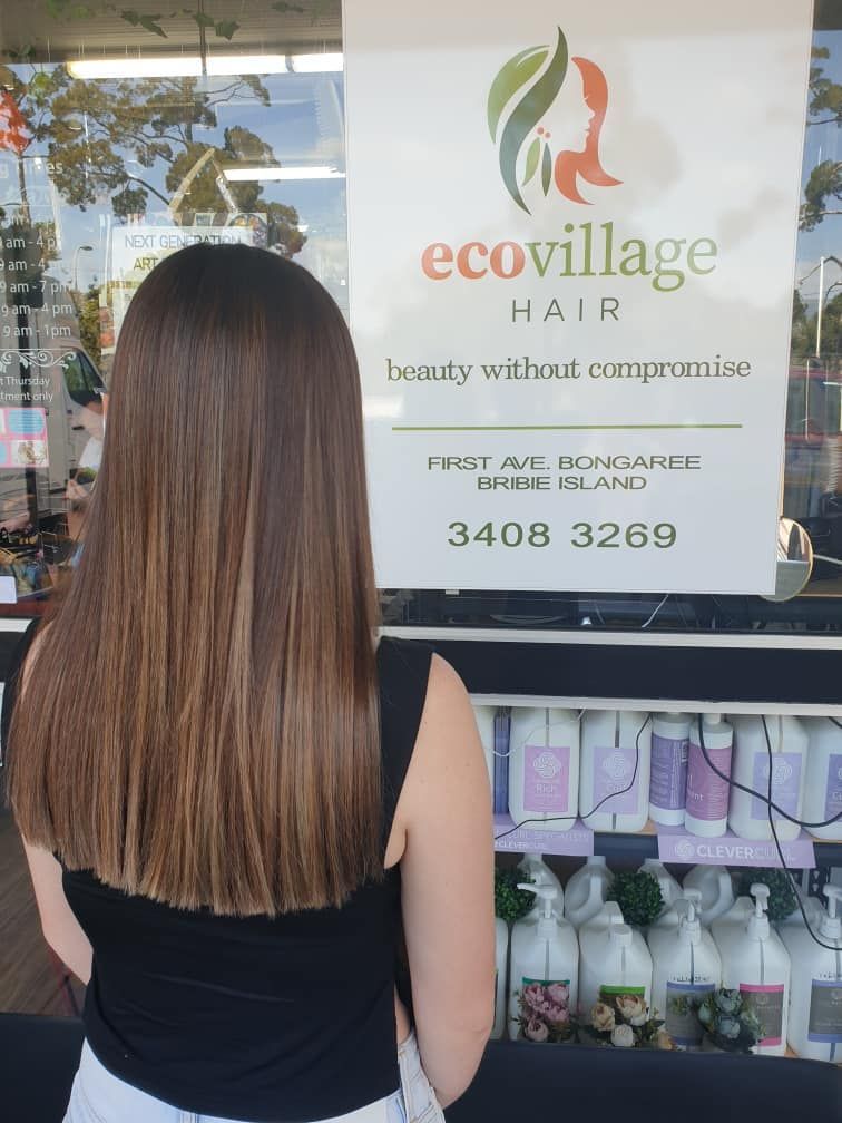 A Woman is Standing in Front of a Sign That Says Ecovillage Hair — Eco Village Hair in Bongaree, QLD
