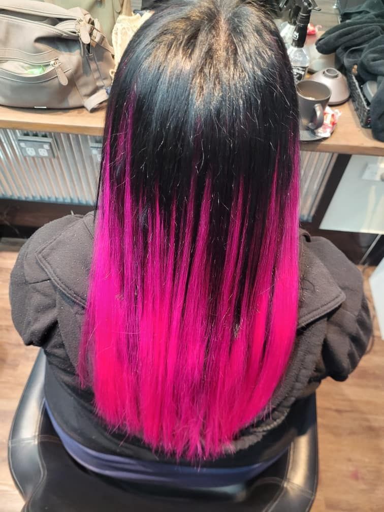 A Woman With Black Hair and Pink Highlights is Sitting in a Chair — Eco Village Hair in Bongaree, QLD