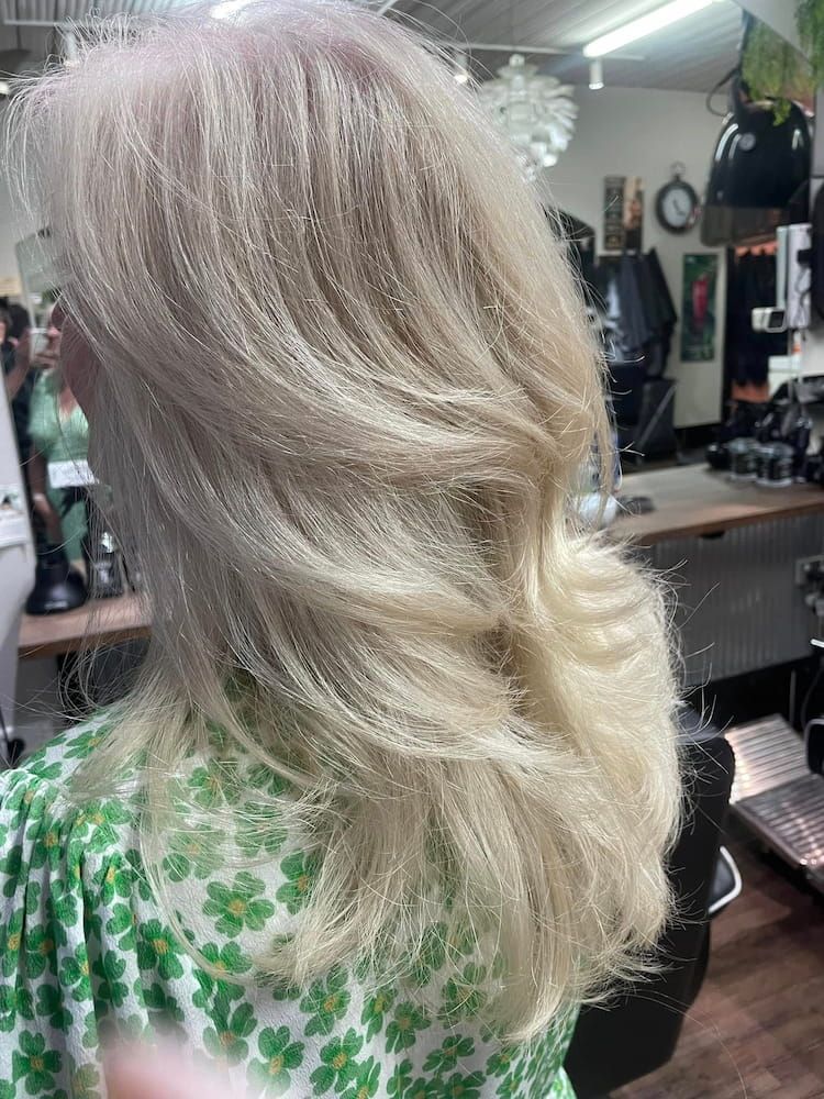 A Woman With Blonde Hair is Sitting in a Chair in a Salon — Eco Village Hair in Bongaree, QLD