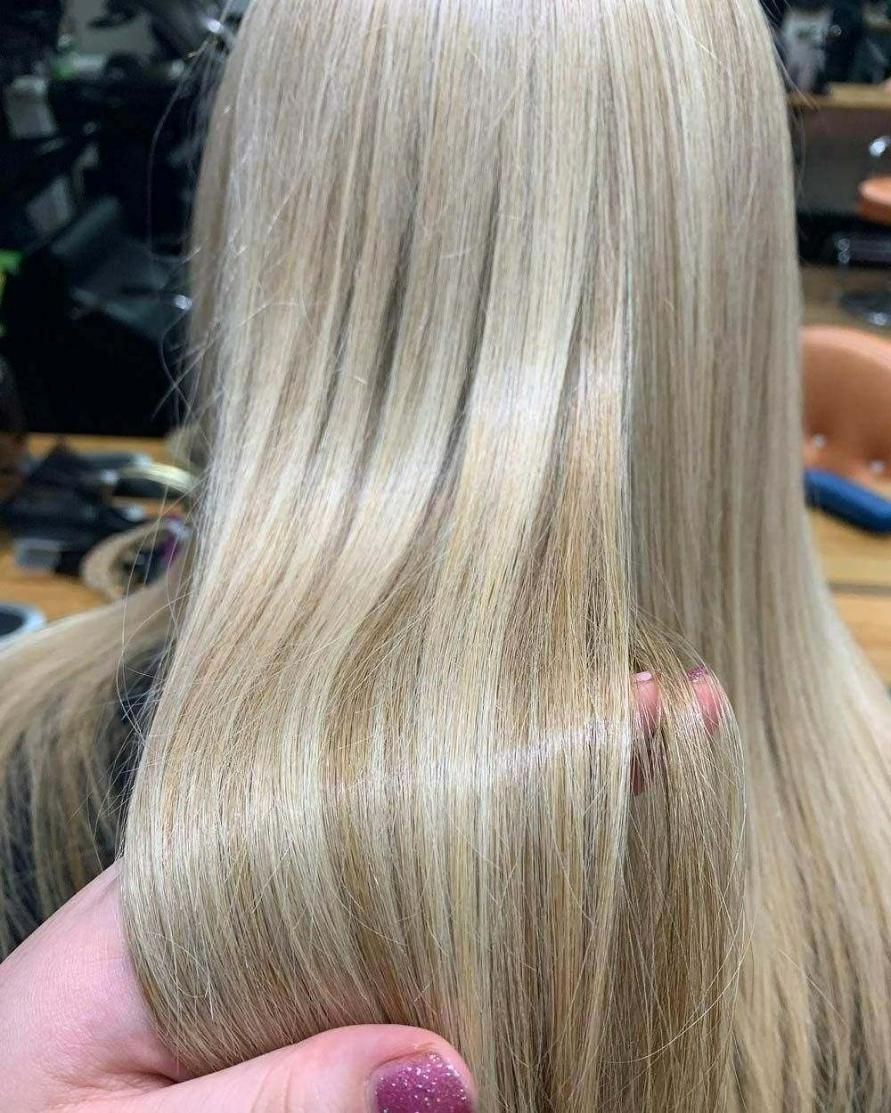 A Woman Is Holding Her Blonde Hair in A Salon — Eco Village Hair in Bongaree, QLD