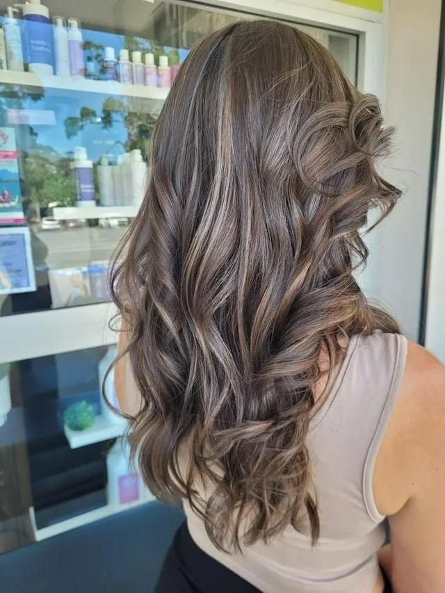 A Woman with Long Brown Hair in Front of A Shelf of Hair Products — Eco Village Hair in Bongaree, QLD