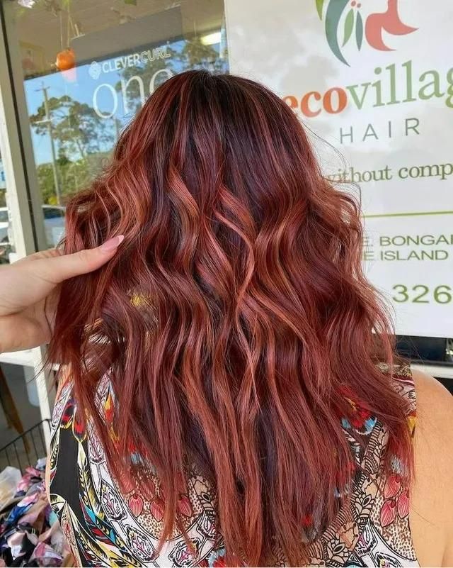 A Woman with Long Red Hair Is Standing in Front of A Sign that Says Eco Village Hair — Eco Village Hair in Bongaree, QLD
