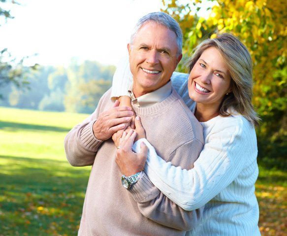 Smiling Couple Embracing Outdoors on a Sunny Day — Wide Bay Chiropractic in Gympie, QLD