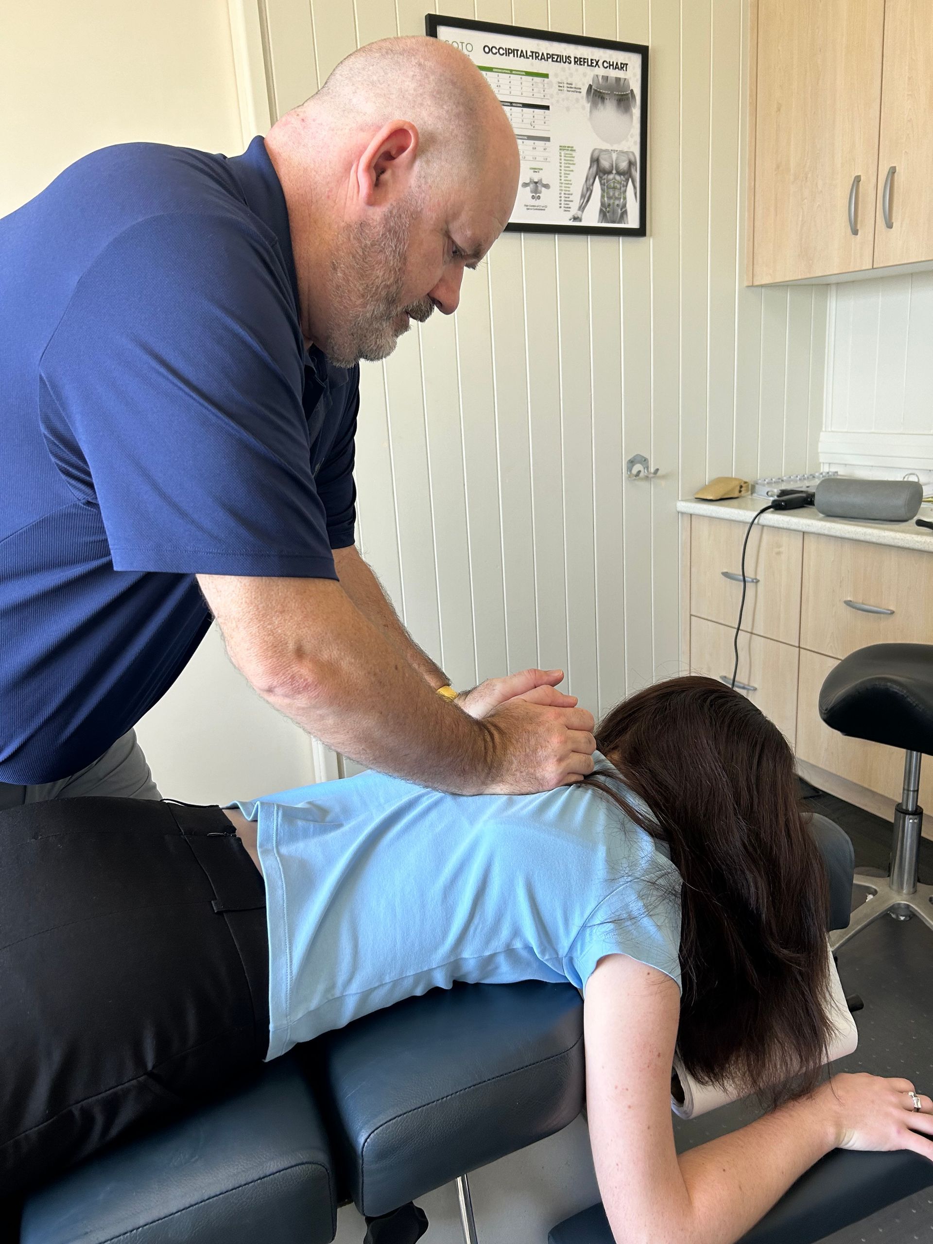 A Woman in Blue Shirt Examines Another Woman’s Neck — Wide Bay Chiropractic in Gympie, QLD